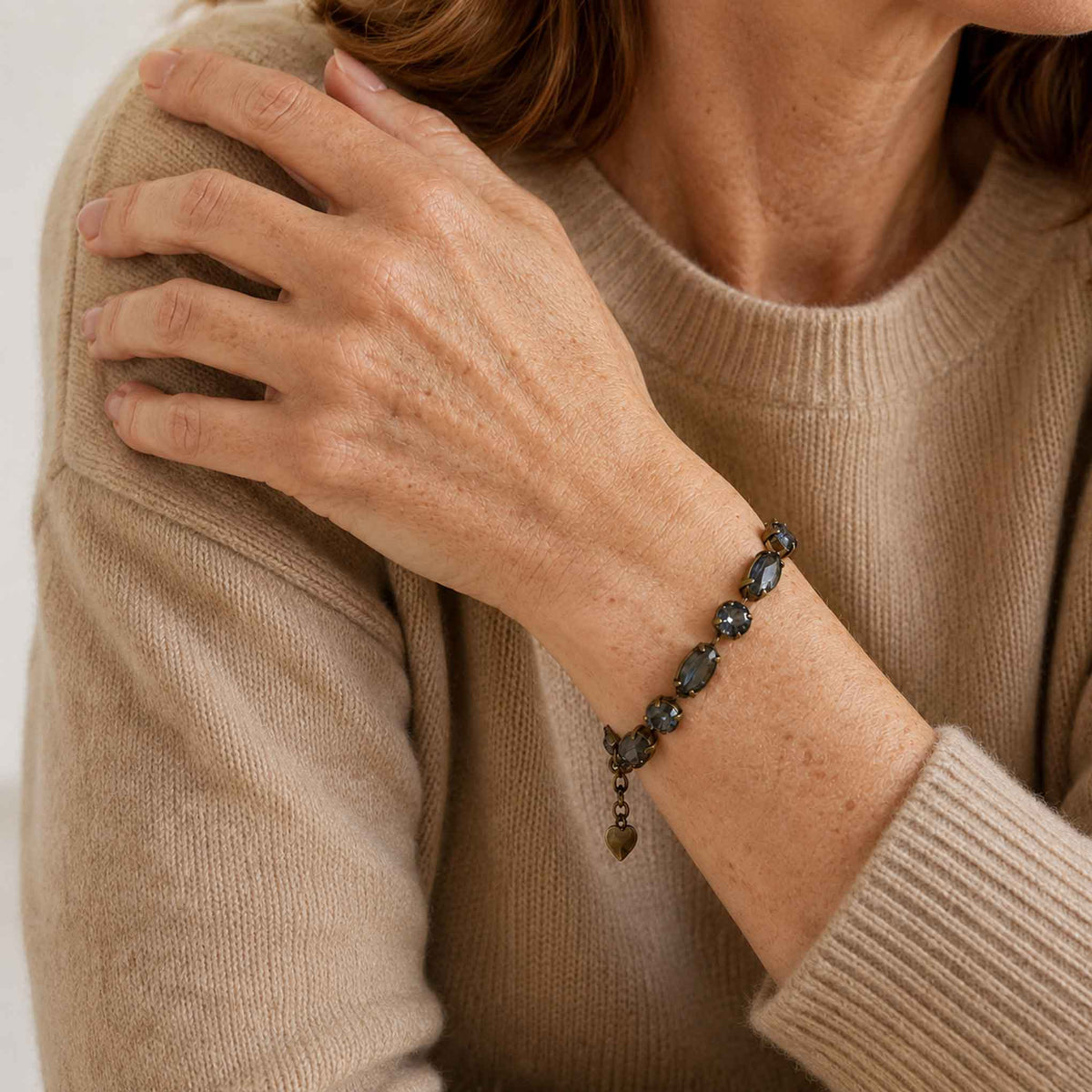 Model wearing antique brass and black diamond bracelet with a camel colored cashmere sweater.