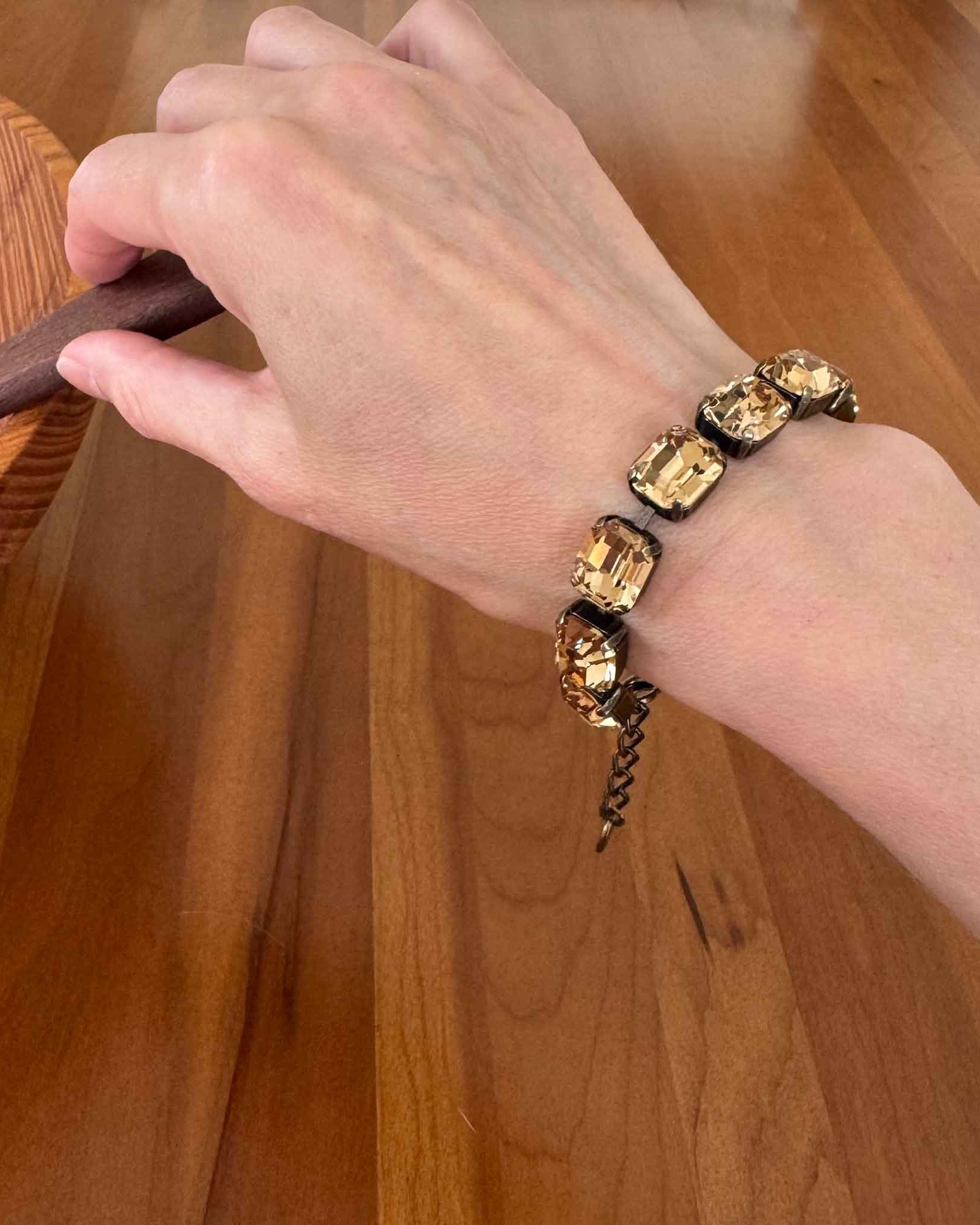Light Colorado topaz crystal bracelet by Petite Margaux shown on a wrist. Emerald cut in antique brass setting.