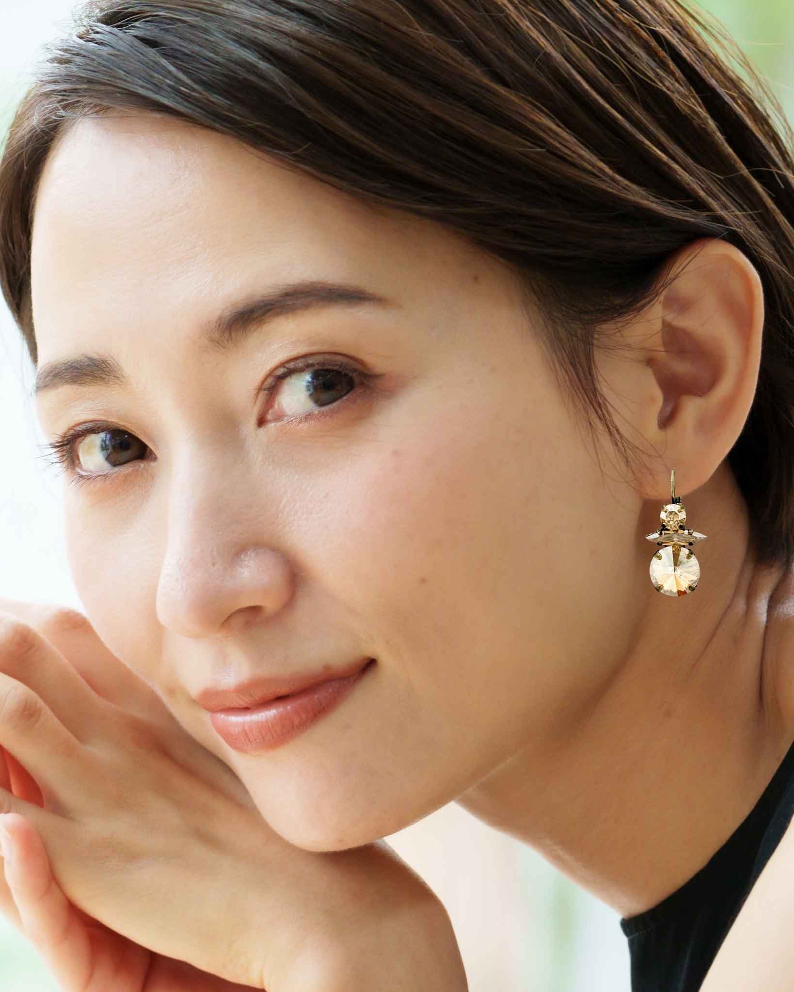 Asian model wearing citrine colored crystal earrings.
