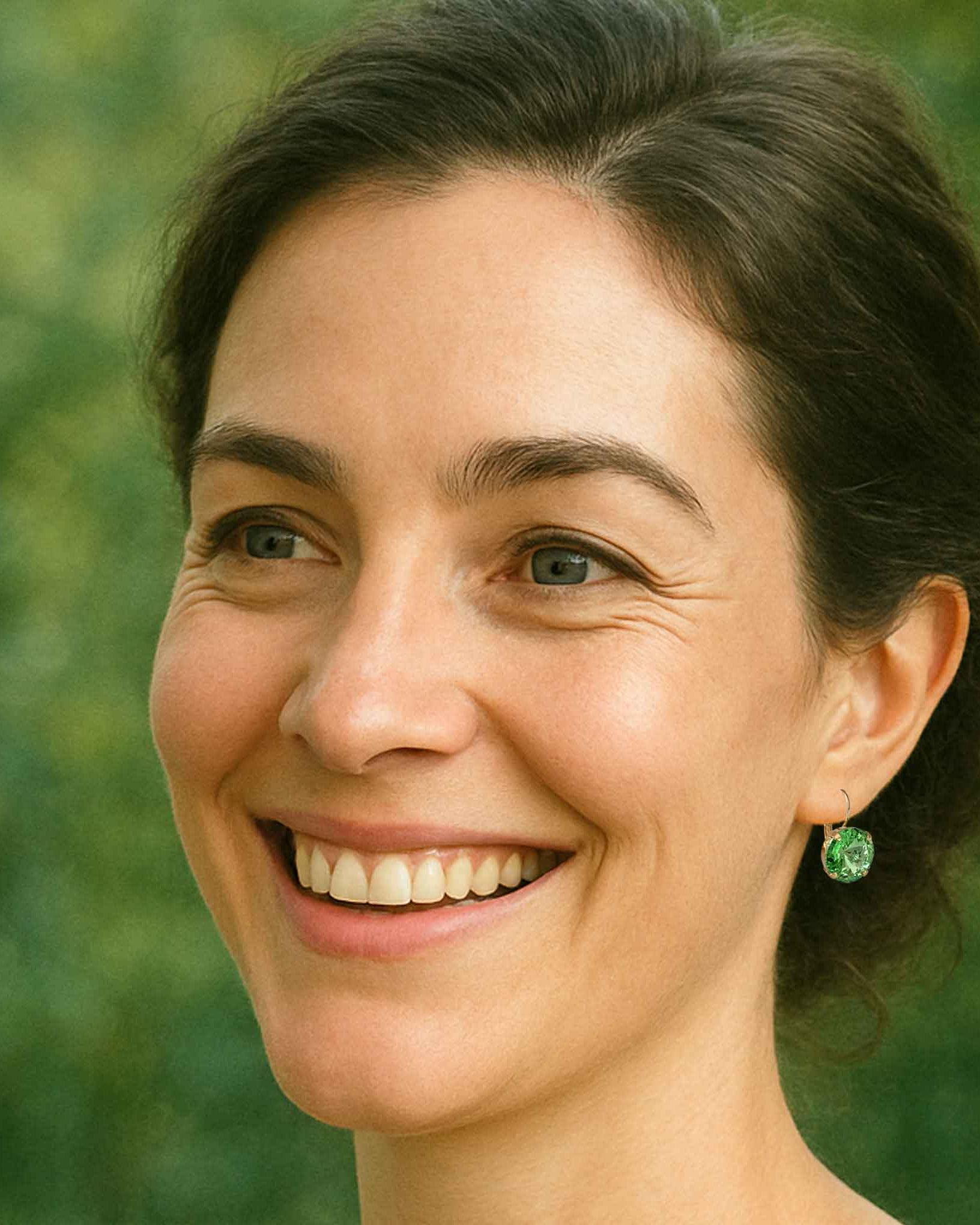 Woman wearing green crystal earrings by Petite Margaux.