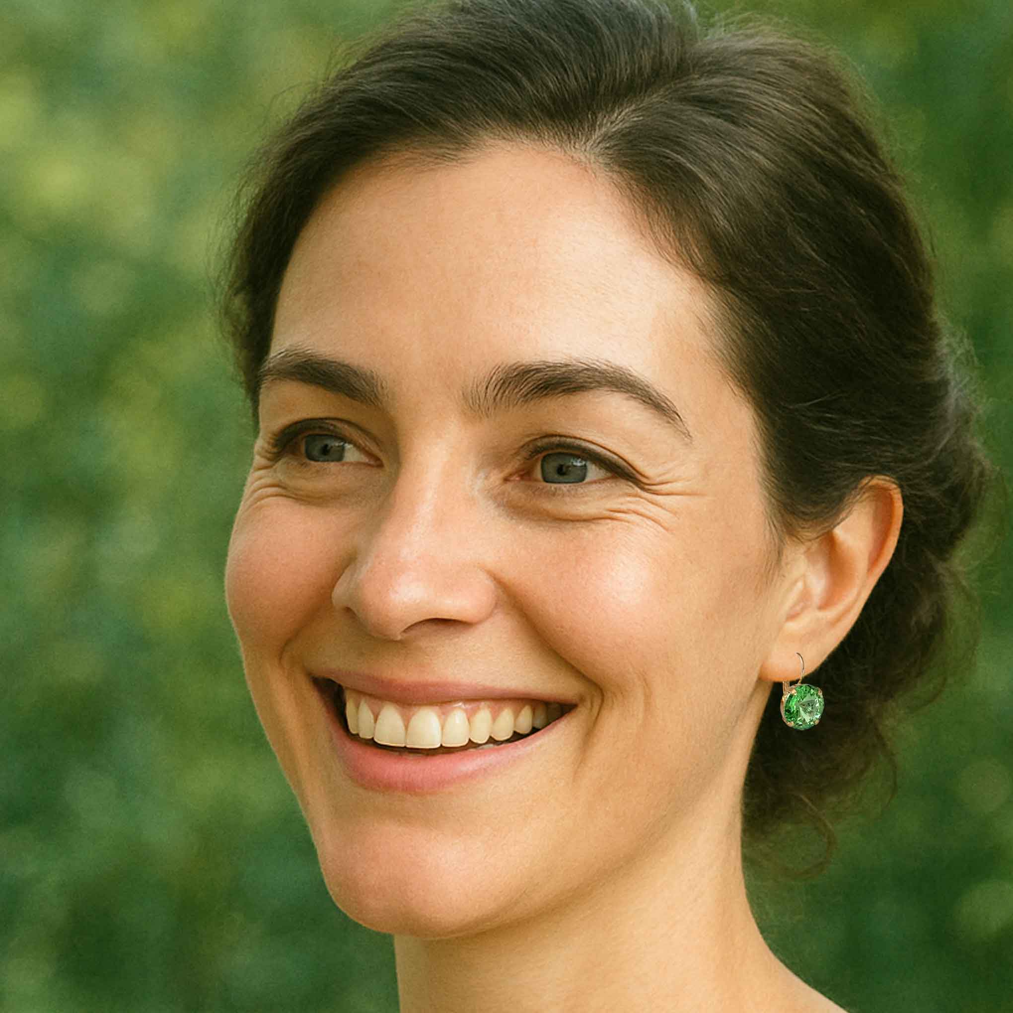 Woman wearing green crystal earrings by Petite Margaux.