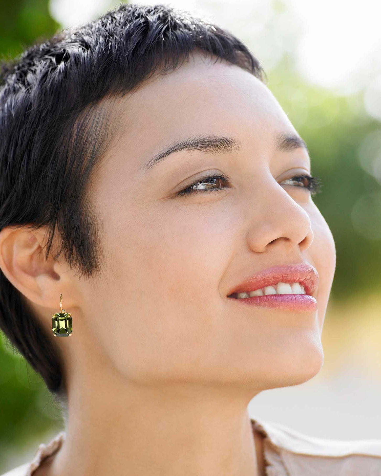 Woman wearing rectangular olive green rhinestone drop earrings.
