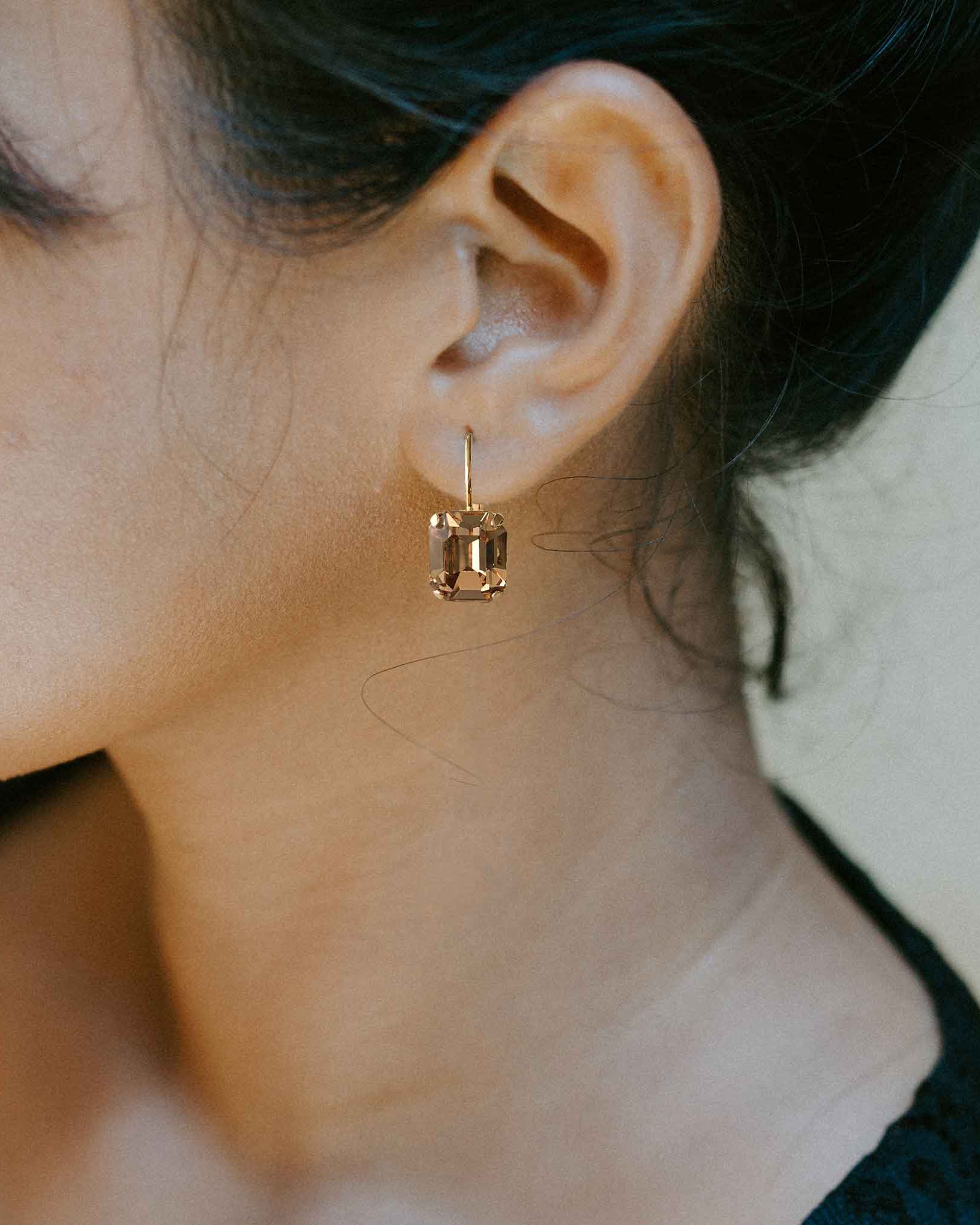 Model wearing emerald cut light topaz crystal earrings by Petite Margaux.