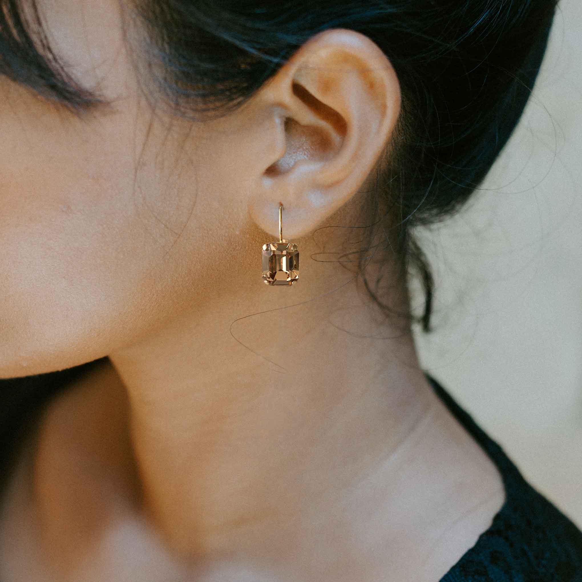 Model wearing emerald cut light topaz crystal earrings by Petite Margaux.