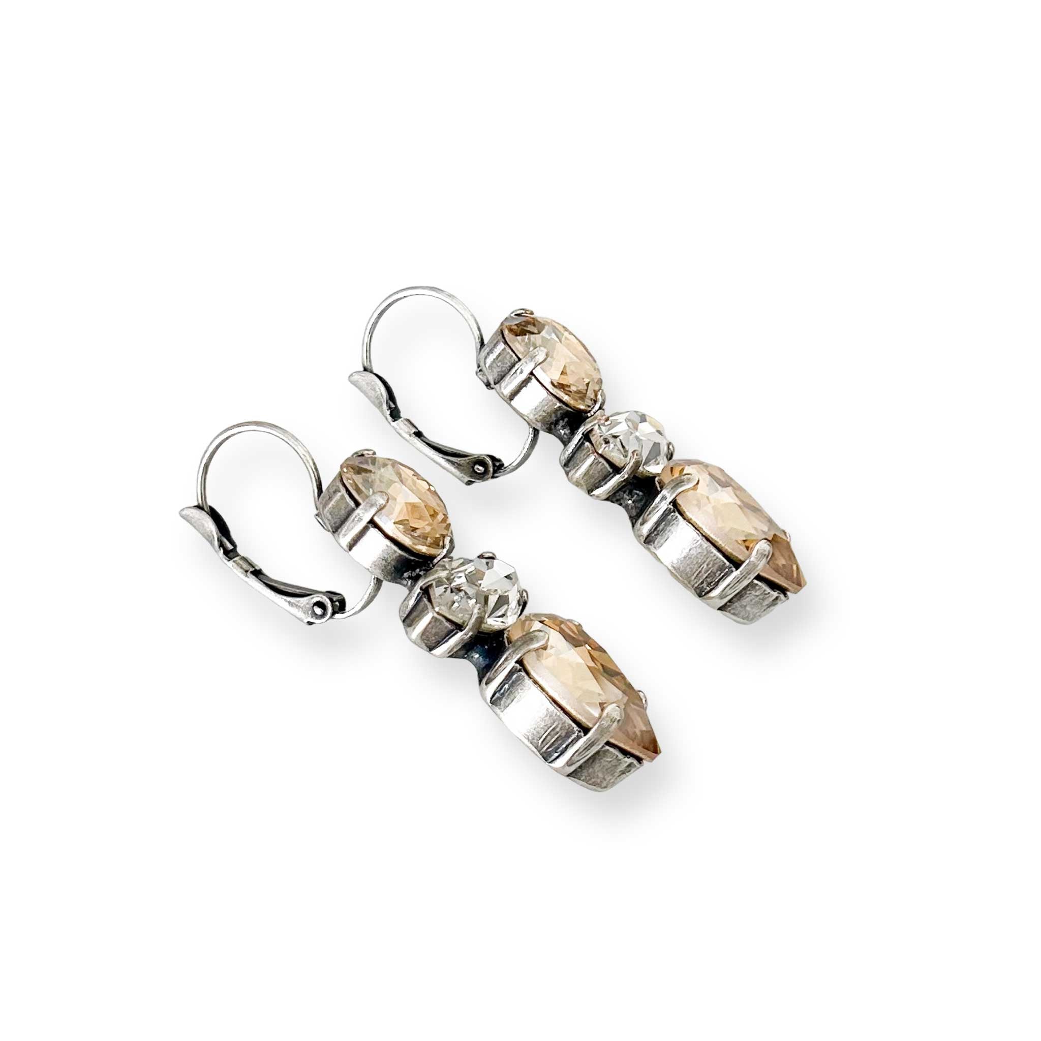 Side view of silver and champagne color crystal earrings.