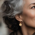 Close-up of brown crystal earrings on a mature woman.