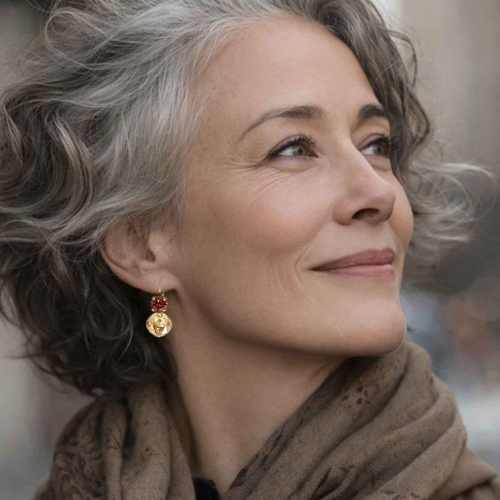 Close-up of brown and gold crystal earrings on a stylish mature woman.