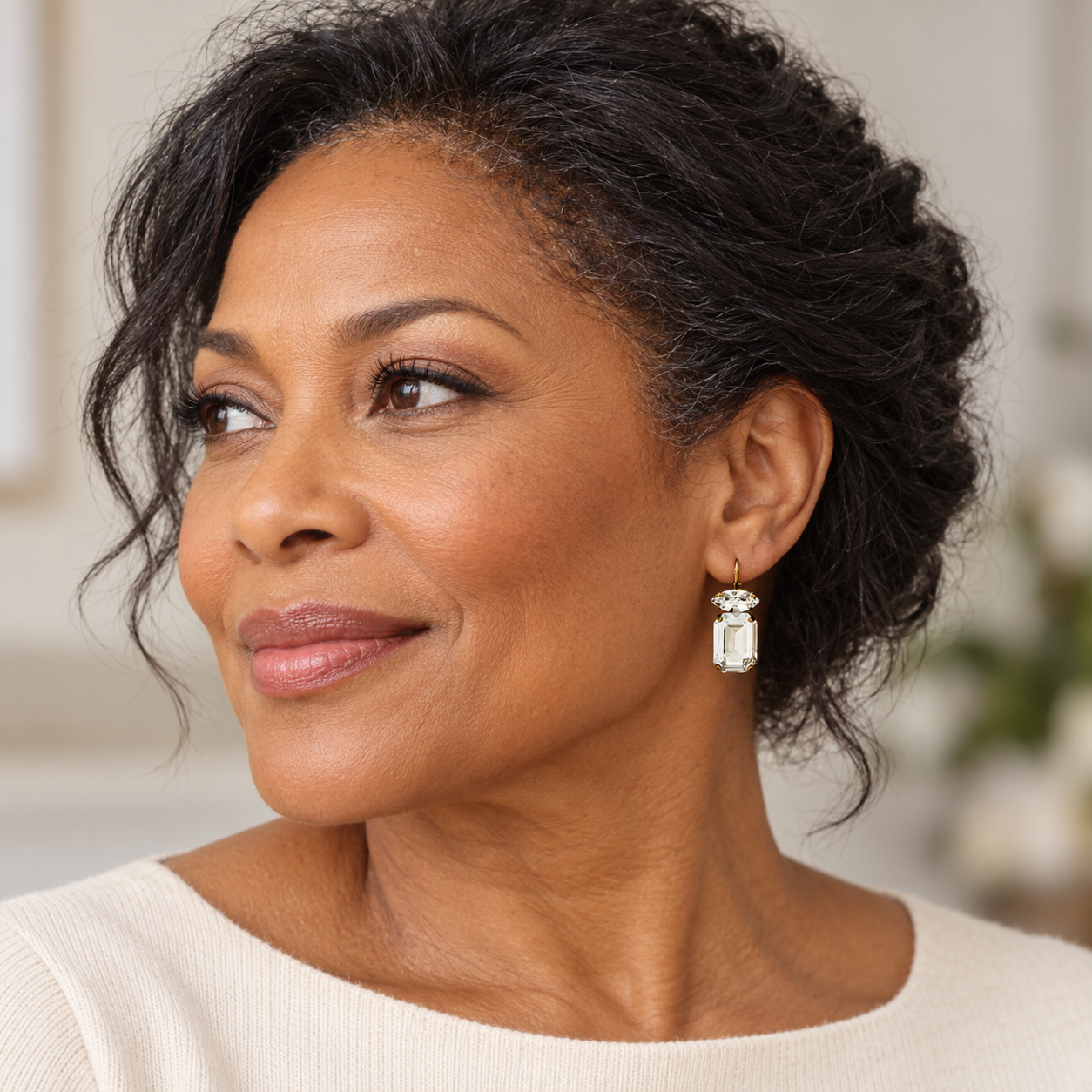 Attractive middle-aged black woman wearing clear, emerald-cut crystal earrings by Petite Margaux.