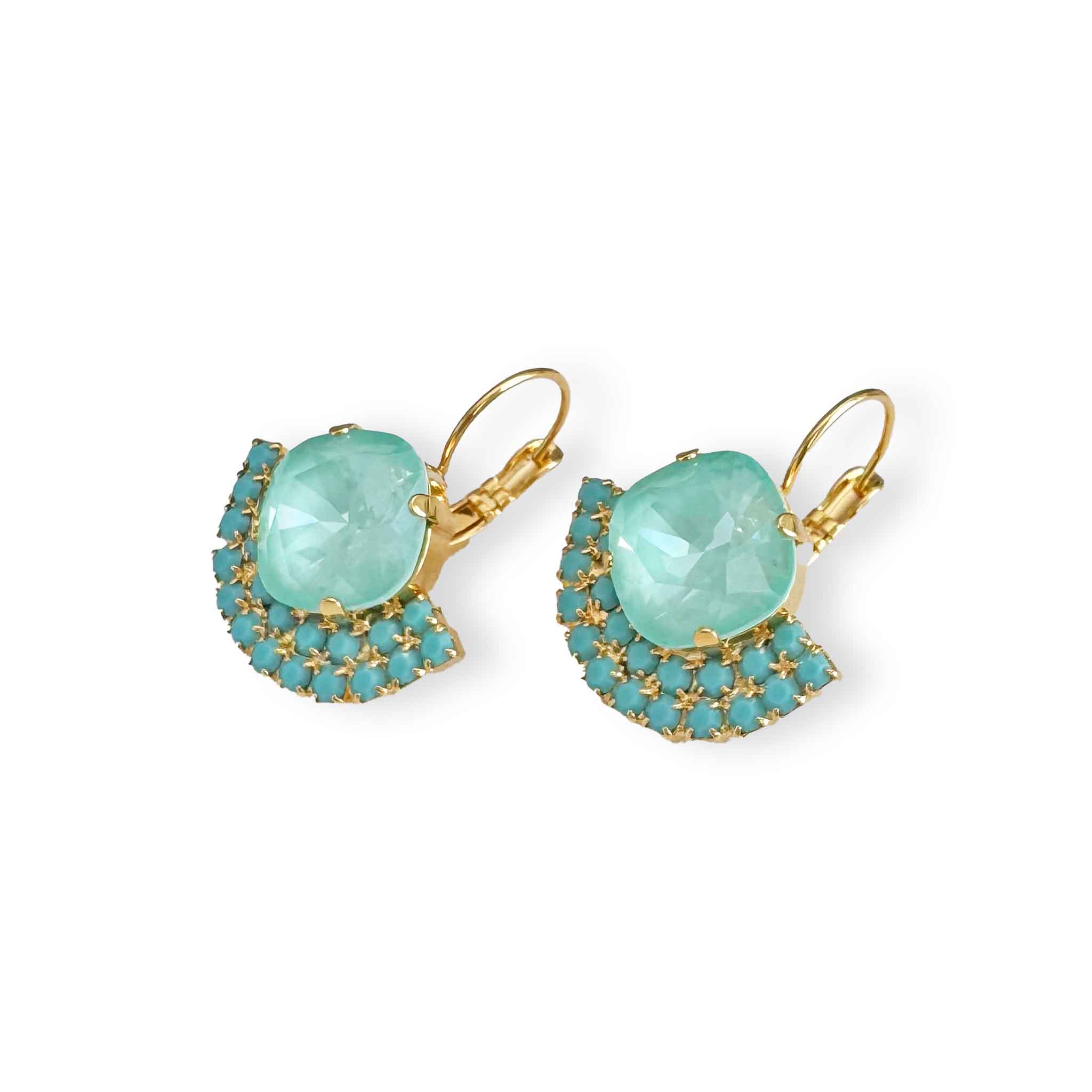 Angled view of light turquoise and mint green crystal drop statement earrings shown in gold.