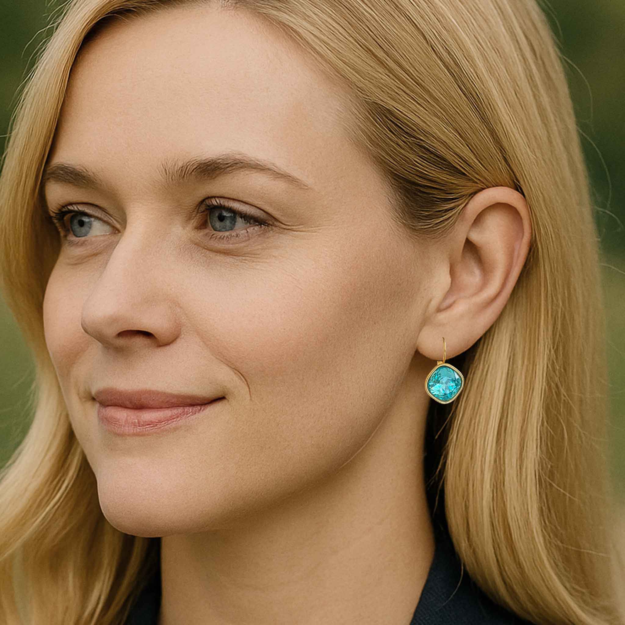 Young woman wearing aquamarine colored earrings by Petite Margaux.