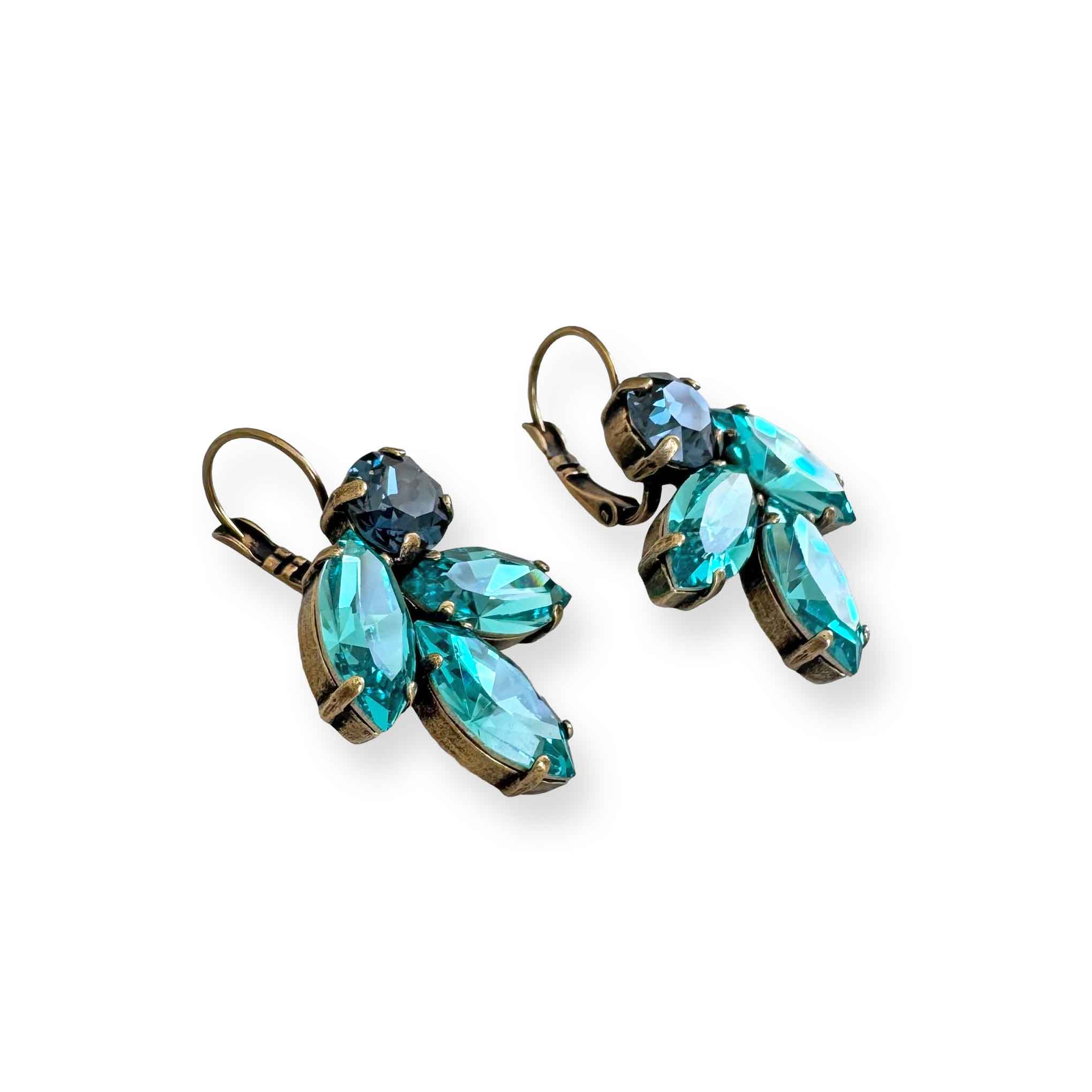 Side view of aqua turquoise and blue sapphire crystal earrings in a leaf motif in antique brass finish.
