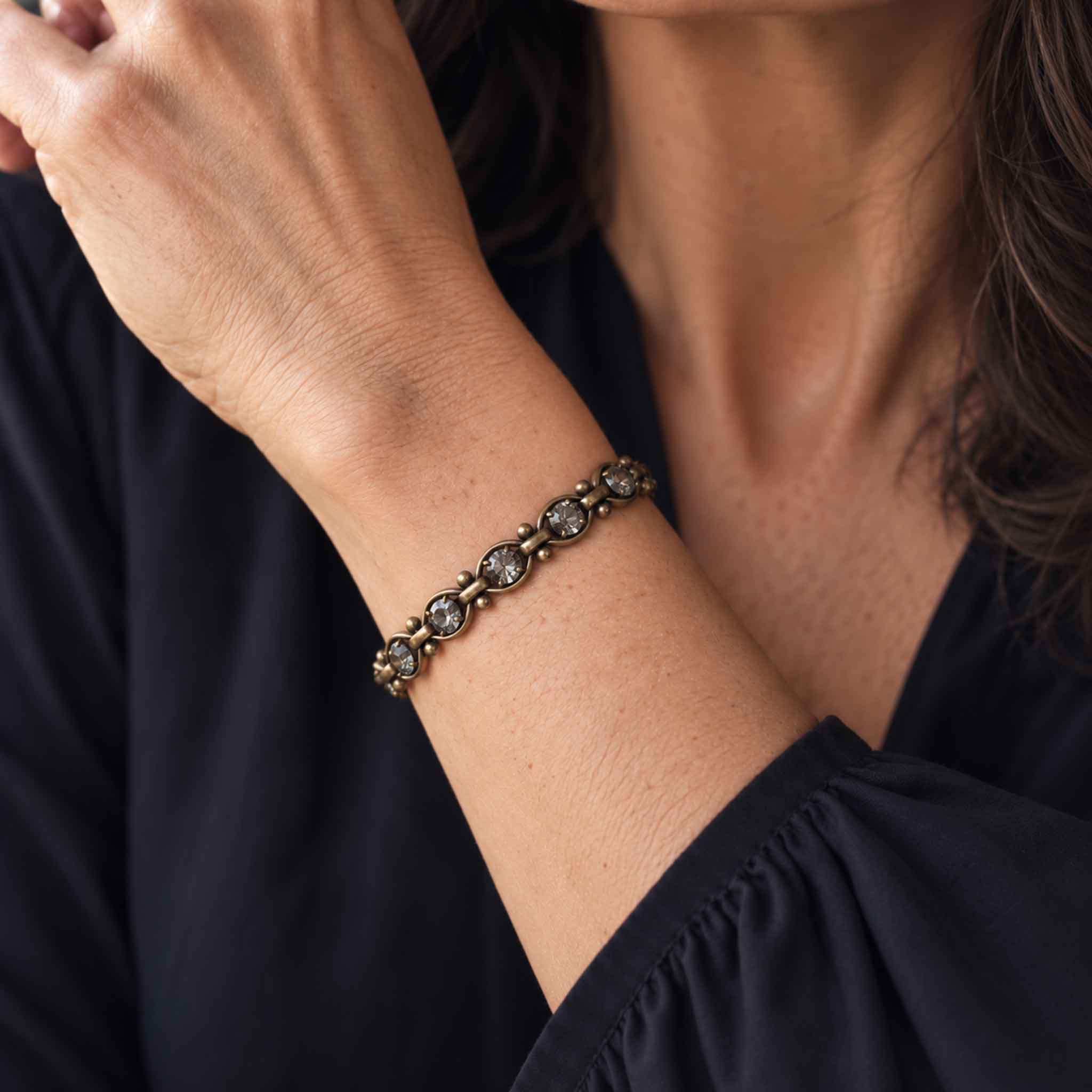 Black diamond crystal bracelet with antique brass links shown on a wrist.