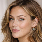 Close-up of a woman with dark blonde hair wearing black fan-shaped crystal earrings by Petite Margaux.