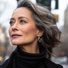 Stylish mature woman wearing black diamond rhinestone earrings with a black turtleneck.