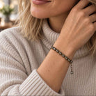 Woman in cream turtleneck wearing black diamond crystal bracelet in antique brass.
