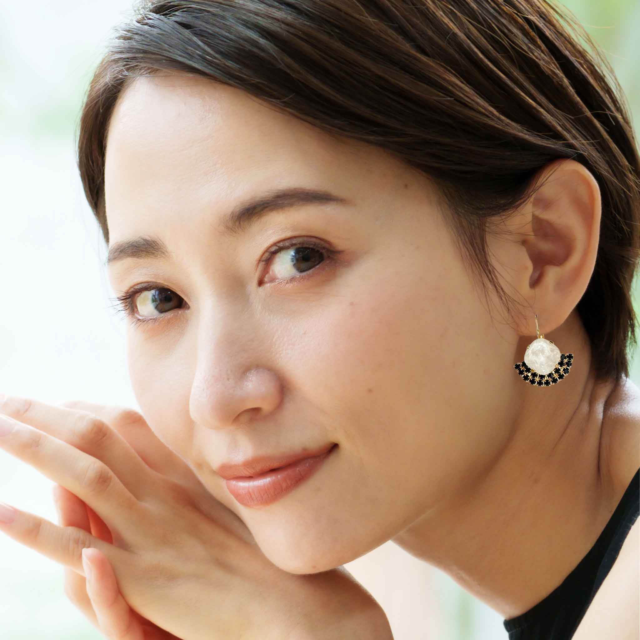 Young woman wearing black and white crystal drop earrings.