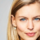 Blond woman wearing gold and linen white crystal earrings.