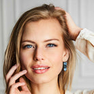 Woman modeling blue crystal statement earrings by Petite Margaux.
