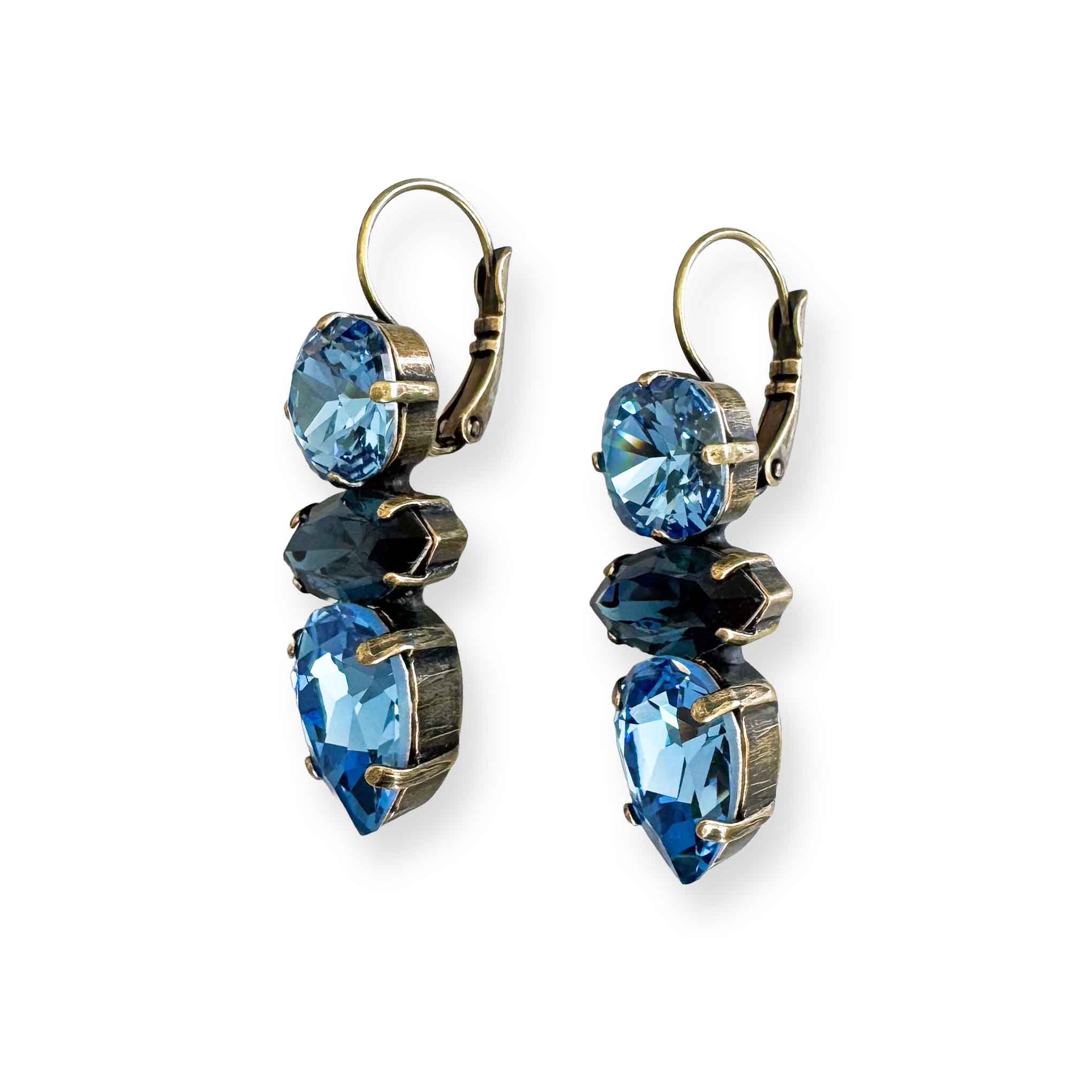 Angled view of light and dark blue crystal earrings showing antique brass finish.