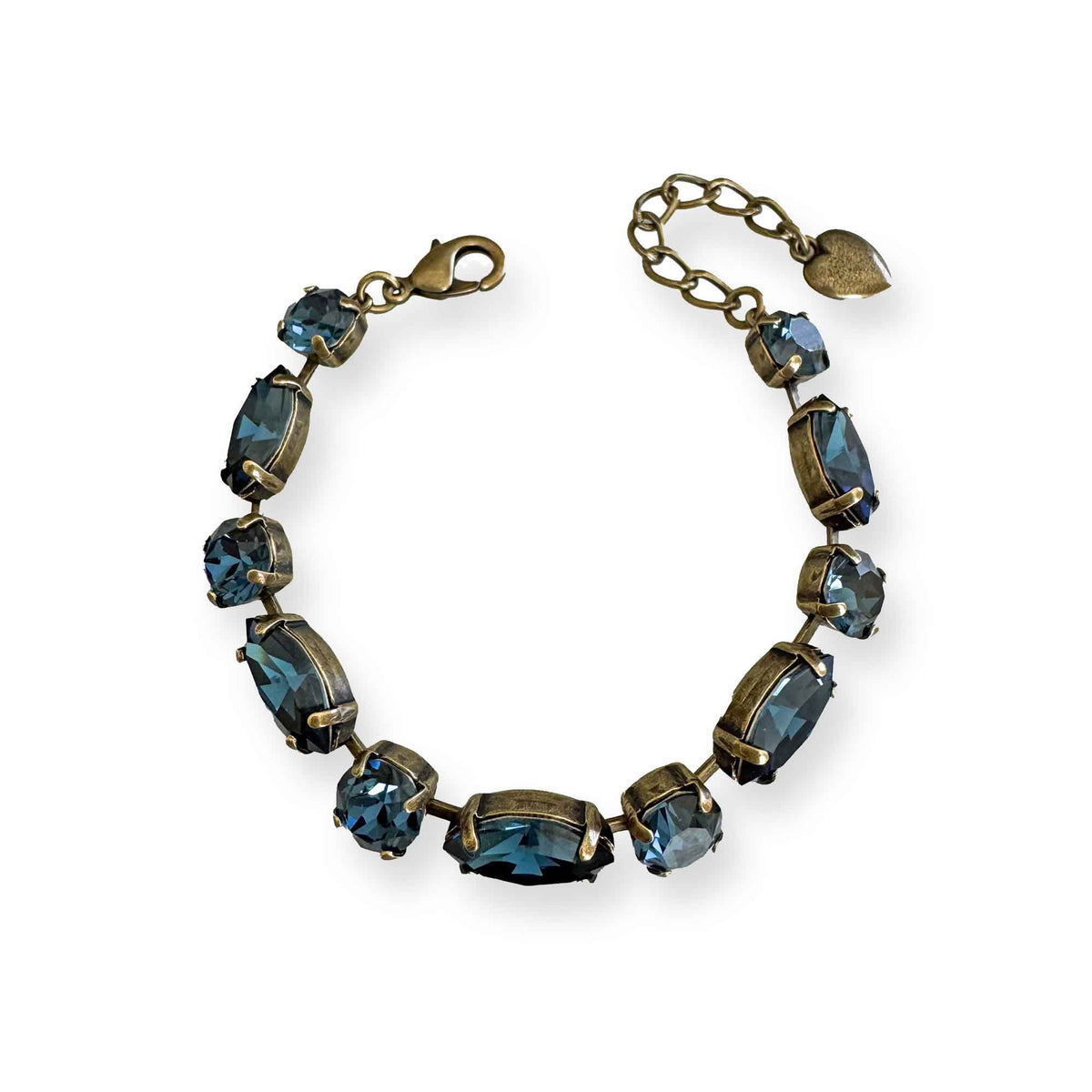 Antique brass bracelet with alternating oval and round denim blue crystals laid flat on a white background.