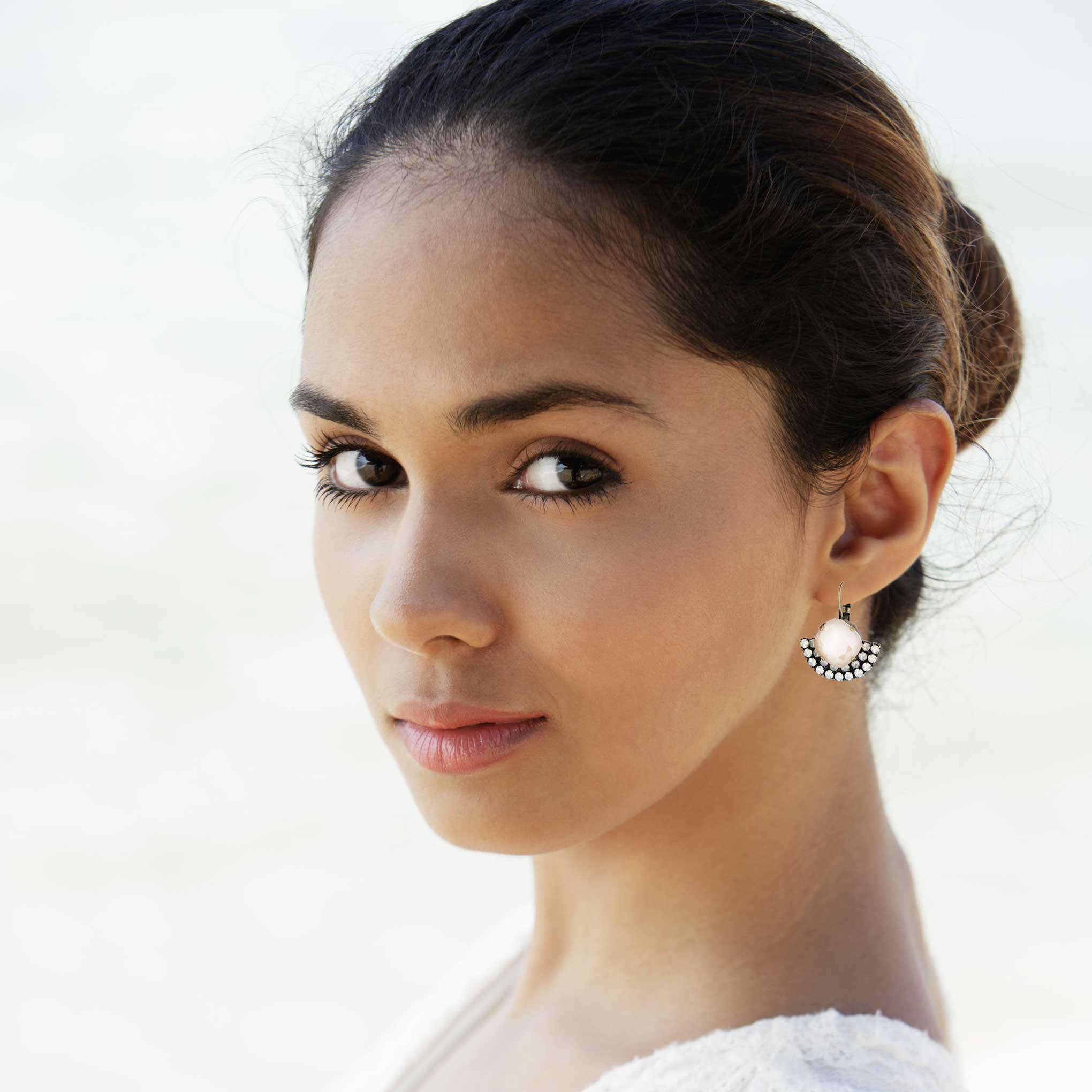 Bride wearing ivory cream blush colored crystal earrings in silver fan shape.