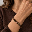 Woman in brown sweater wearing dark brown topaz crystal bracelet with antique brass links.