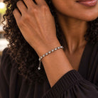 Black woman wearing antique silver tennis bracelet with clear Swarovski crystals with a brown top.