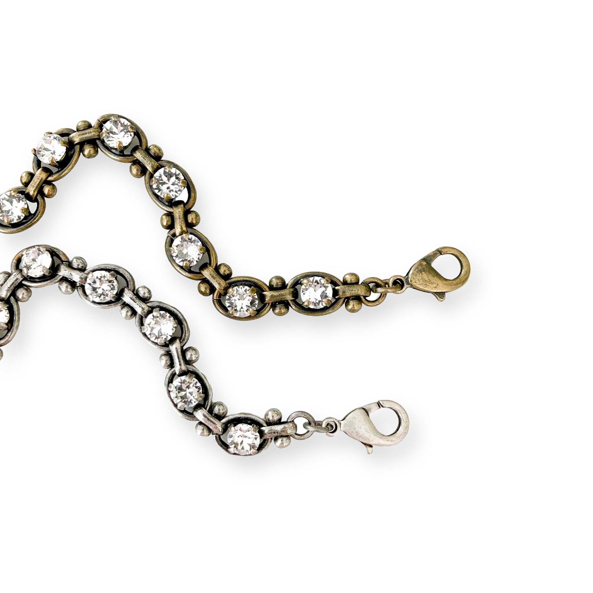 clear crystal link bracelets on a white background in antique brass and antique silver.