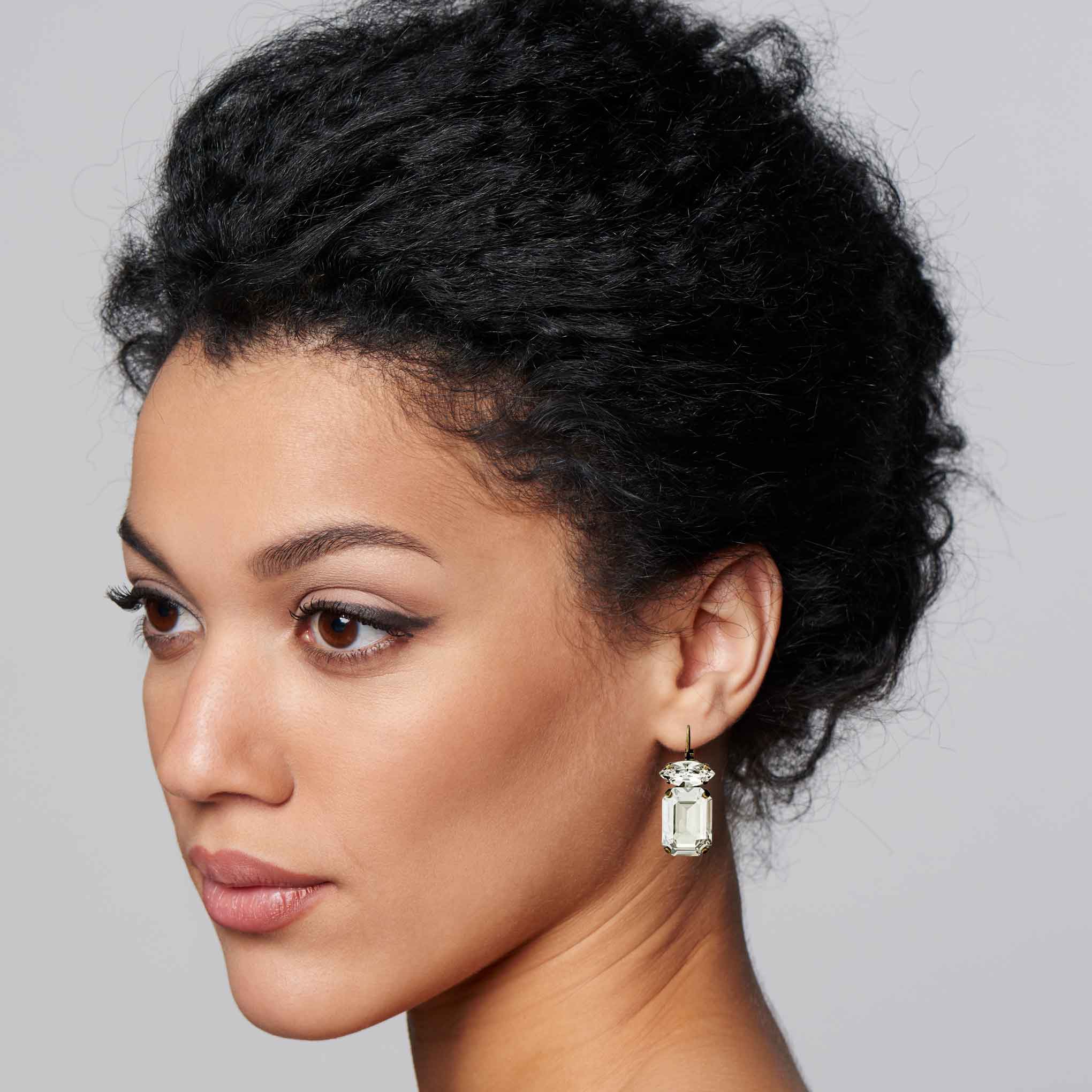 Woman wearing emerald cut clear crystal drop earrings.