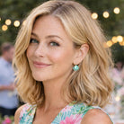 Woman with blonde hair and floral dress in outdoor party setting wearing mint green earrings by Petite Margaux.