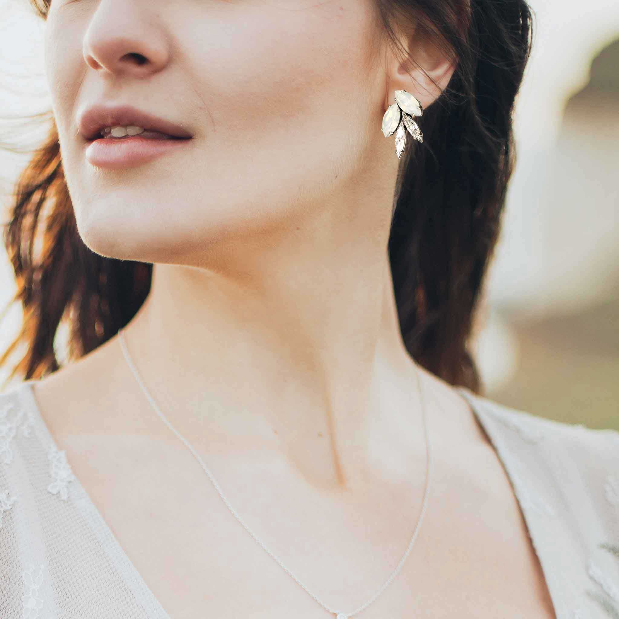 Bride wearing leaf motif stud earrings of white and clear crystals.