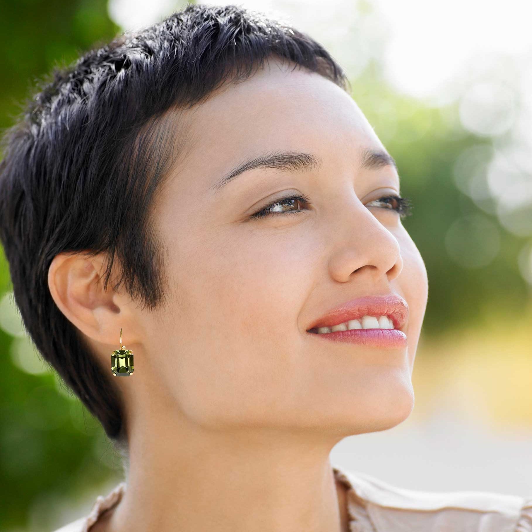 Woman wearing rectangular olive green rhinestone drop earrings.