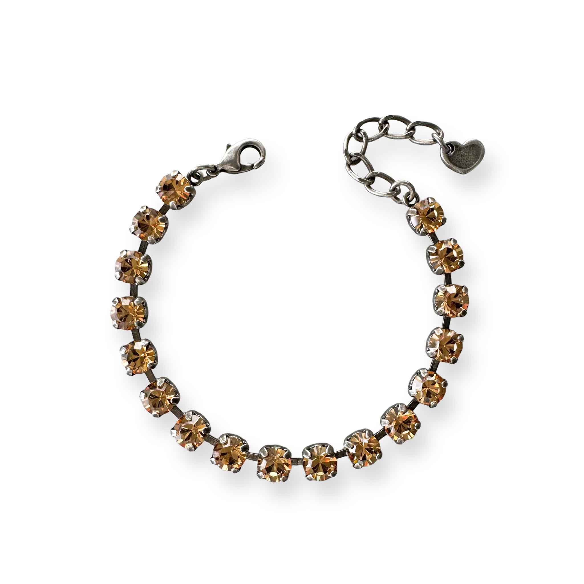 Crystal tennis bracelet of light smoked topaz-colored crystals shown in antique silver.