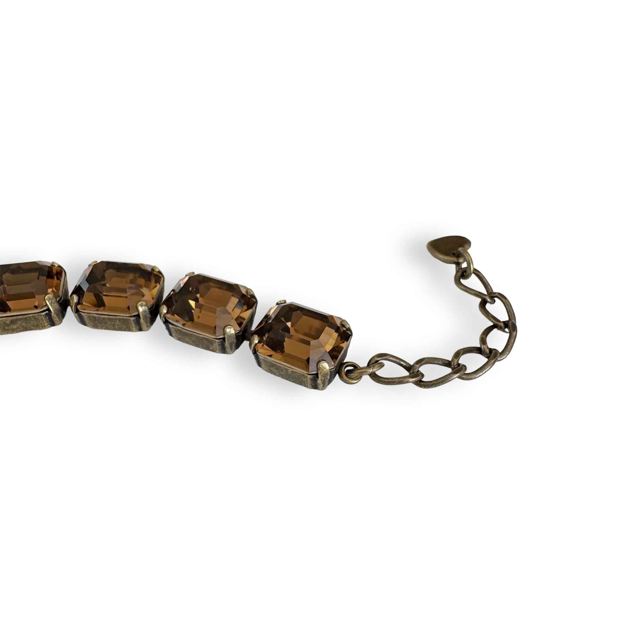 Close up of brown bracelet by Petite Margaux. Fine emerald cut European crystals set in warm antiqued brass with an adjustable extender.