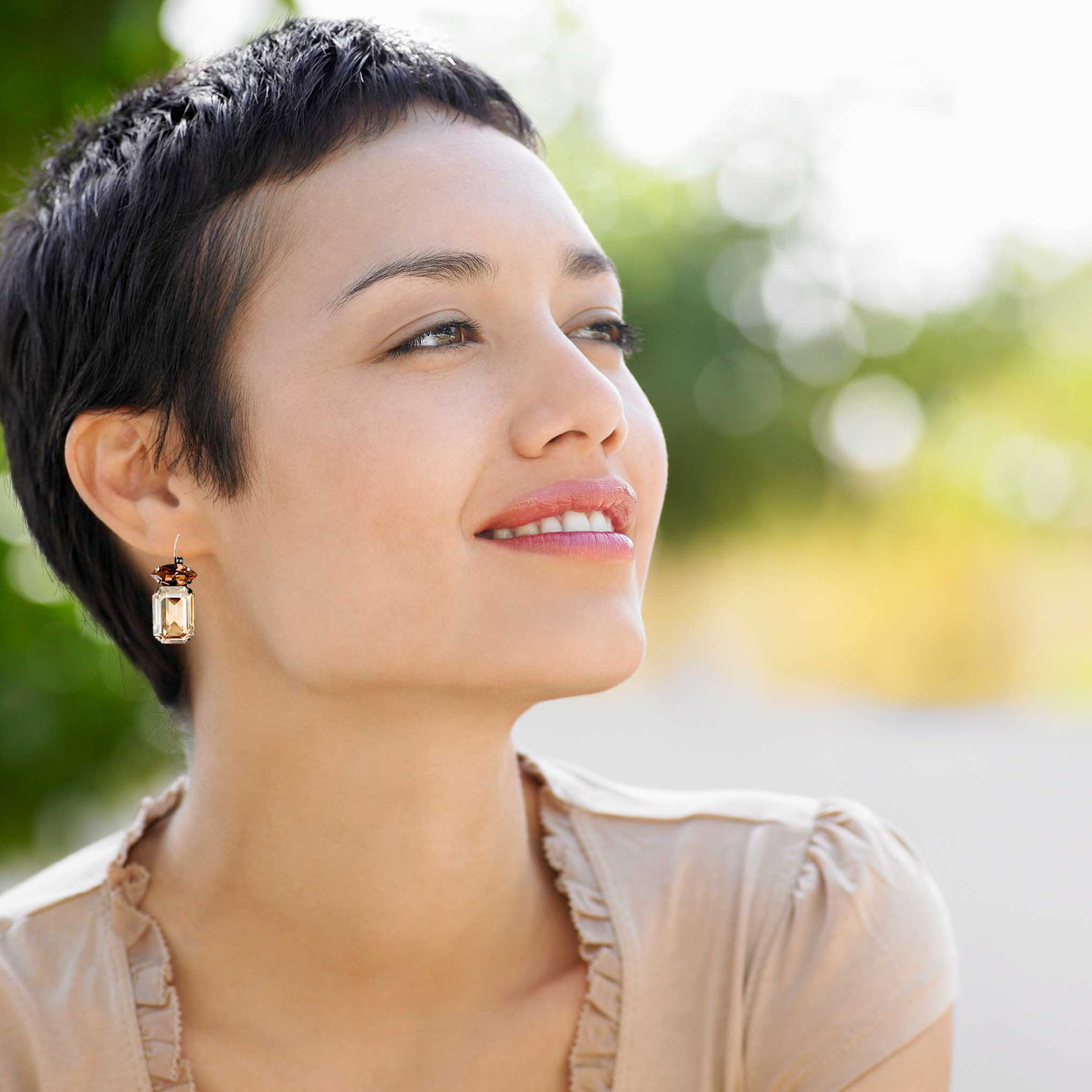 Woman wearing emerald cut yellow and brown topaz colored earrings.