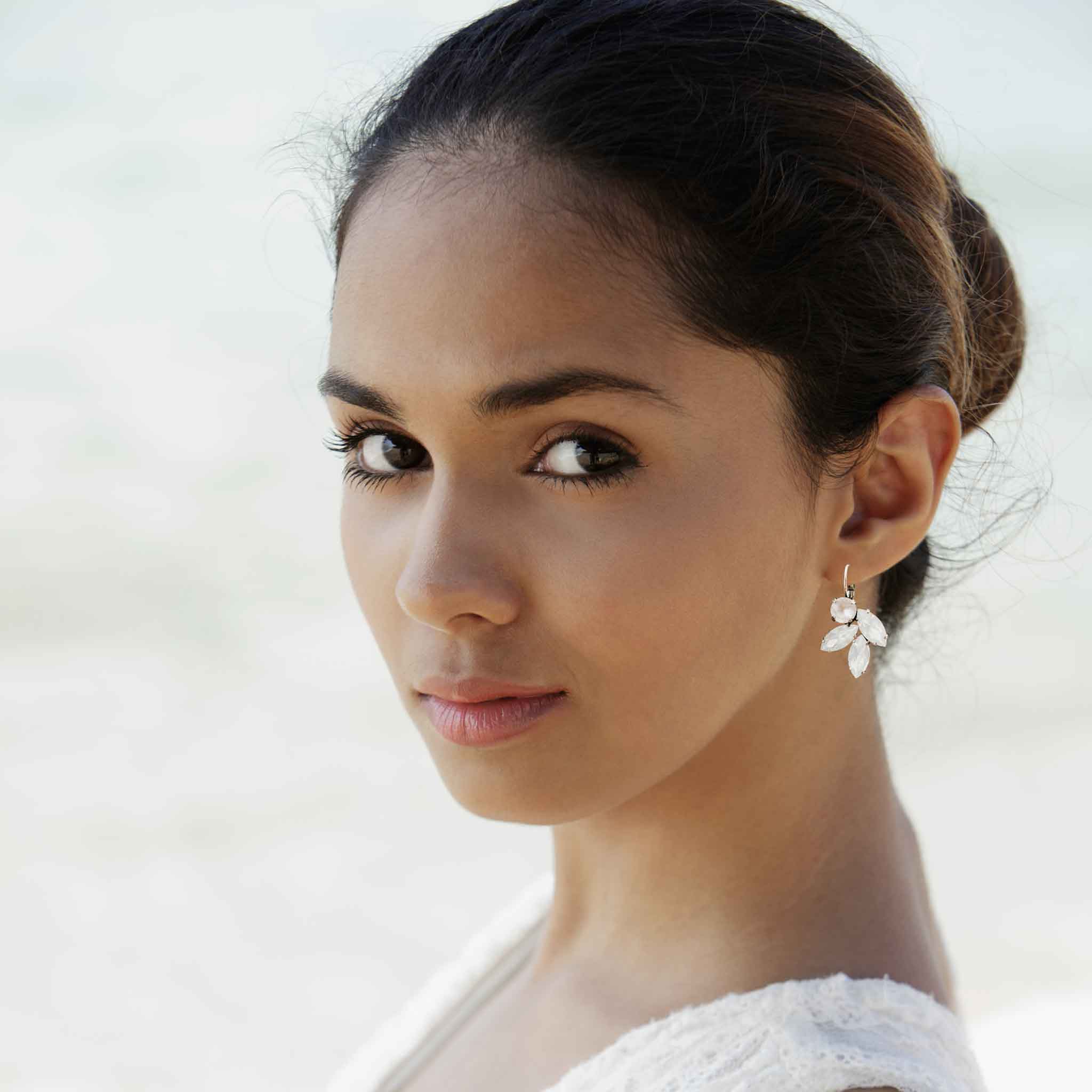 Bride wearing white opal crystal earrings by Petite Margaux.