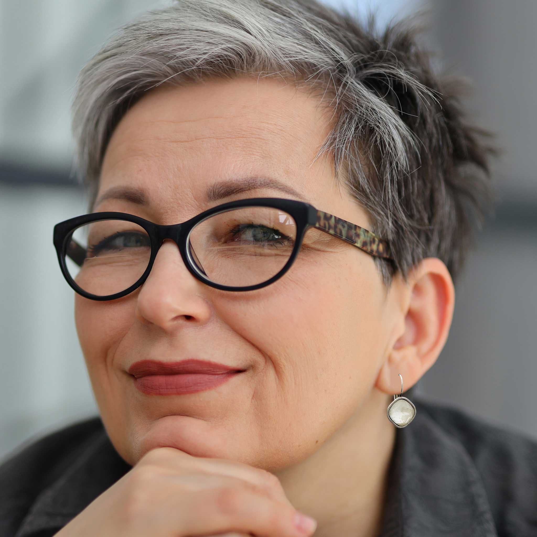 Artsy boomer woman wearing white and silver crystal drop earrings.